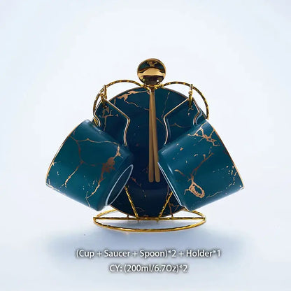Elegant marble ceramic tea set with teal marble-patterned cups, gold accents, saucers, and spoons on a gold holder