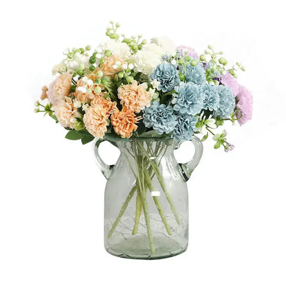 A clear glass vase with two handles holds a decorbites daisy bouquet in pastel pink simulation flowers for living room decor