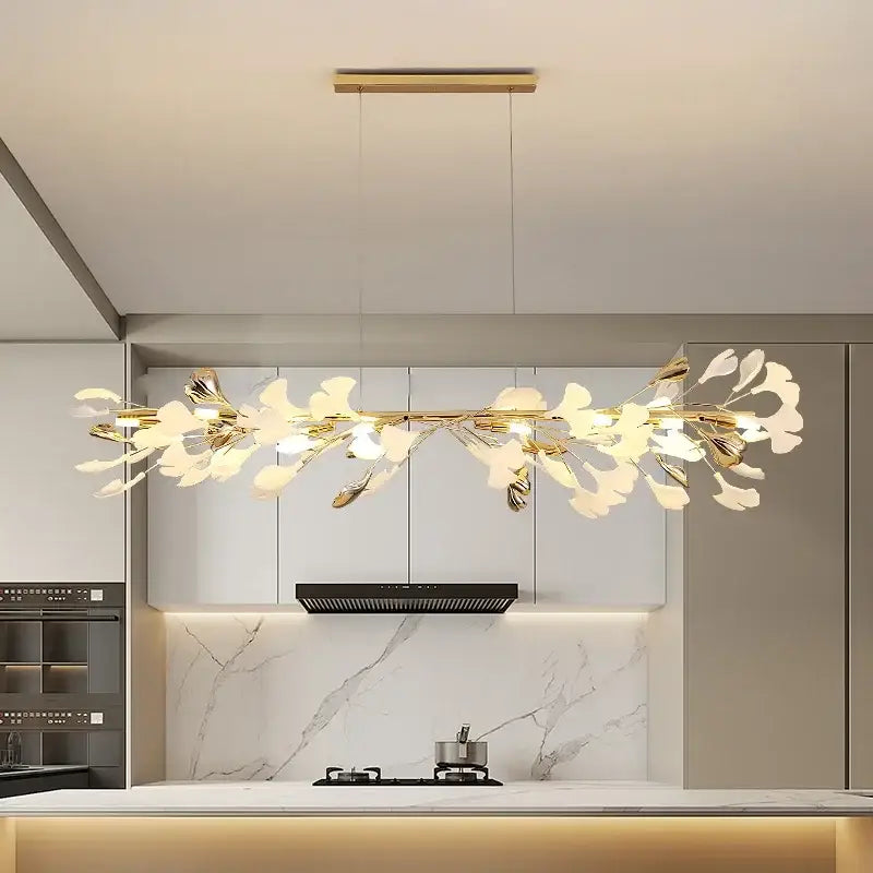 Elegant white and gold ceramic chandelier with gold-toned ginkgo branch pendant light above modern kitchen island