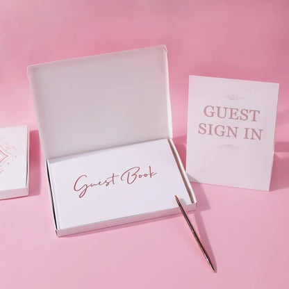 Elegant white guest book with rose gold bronzing detail by decorbites, displayed open with a pen and guest sign in card