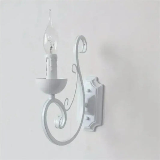Elegant white iron wall lamp with ornate scrollwork and clear glass candle-style bulb by decorbites elegant white