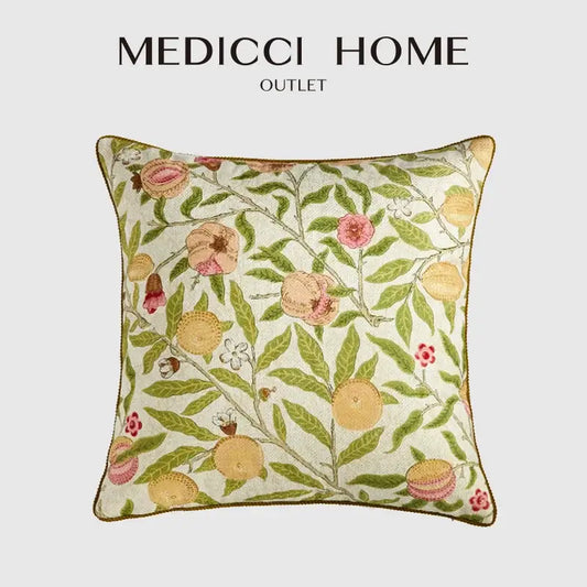 A cream-colored embroidered pillow case with decorbites citron flowers plants featuring pink and yellow fruits and gold-brown trim