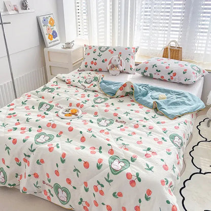 White quilted double gauze comforter with embroidered rabbit print and playful cherry pattern in soft pastel colors