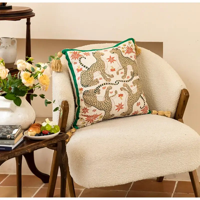 A cream-colored embroidered elephant jungle paradise throw pillow with leopard floral patterns green border tassels decorbites elephant jungle decor