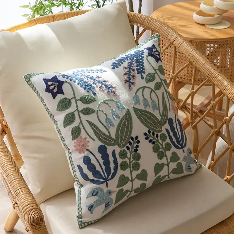 White office cushion pillowcase with intricate embroidered floral and bird patterns in blue green pink and purple