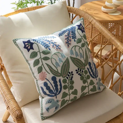 White office cushion pillowcase with intricate embroidered floral and bird patterns in blue green pink and purple