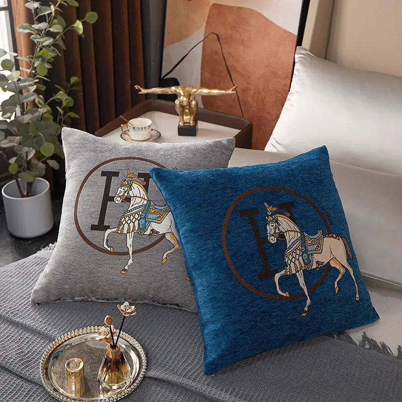 Two embroidered throw pillow covers in heather gray and deep blue featuring white horses with golden harnesses for decorbites cotton home