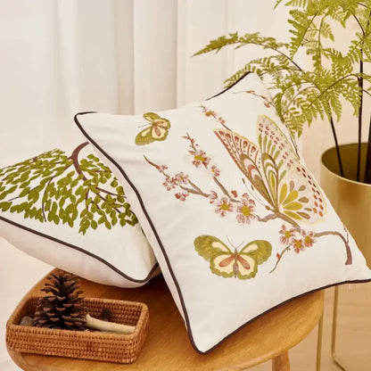White embroidered cushion cover with butterflies and blossoms in green brown and pink hues for living room sofa