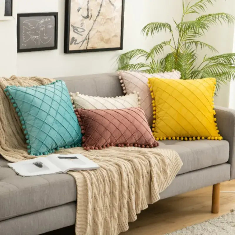 Set of four colorful quilted throw pillows with pom-pom trim in teal dusty rose cream and yellow decorbites corduroy striped design