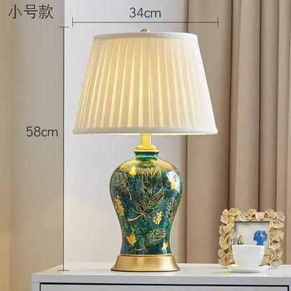Emerald green floral ceramic table lamp with decorbites golden leaf pattern and off-white pleated fabric shade