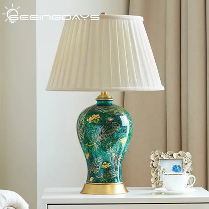 Emerald green floral ceramic table lamp with decorbites golden leaf and pleated cream shade for living room decor
