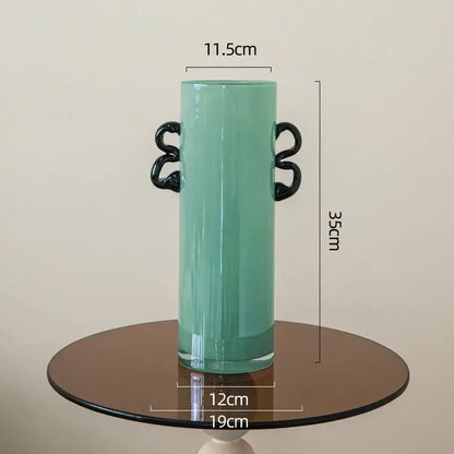 Emerald green glass vase featuring tall translucent teal glass with sleek black twisted handles for living room decor