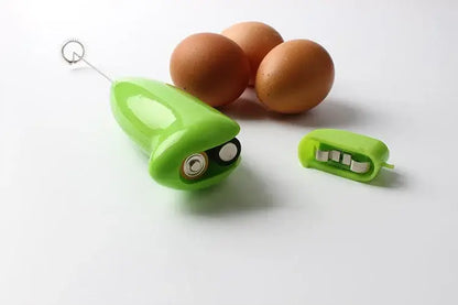 Bright green plastic electric mini mixer with whimsical face design and detachable whisk attachment for kitchen use