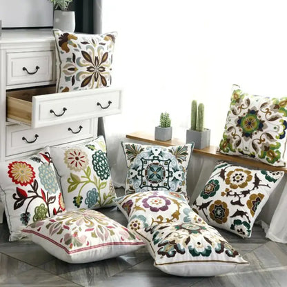 A collection of decorbites ethnic style embroidered pillow covers in vibrant floral and geometric patterns on white canvas