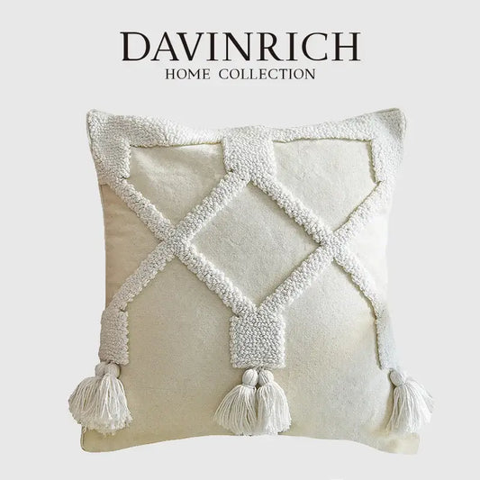 Cream-colored ethnic tufted cushion case with textured white woven diamond pattern and matching tassels for decorbites