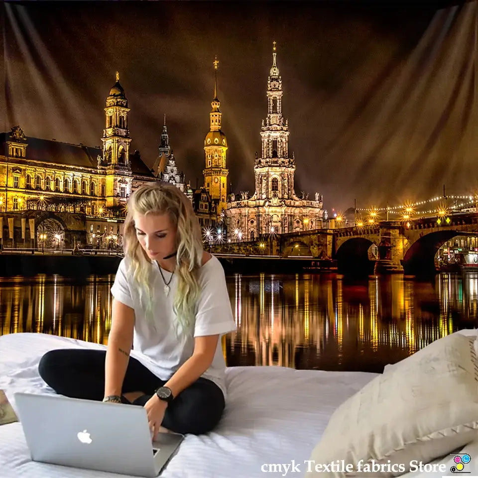 Silver apple laptop placed in front of a european style city night scene tapestry bedroom wall hanging with vibrant colors