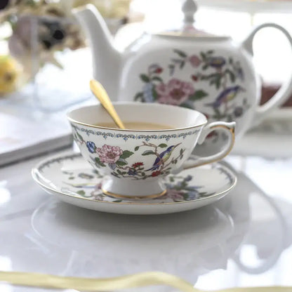 A delicate white porcelain coffee set with intricate floral and bird designs accented by gold trim for elegant decorbites tea