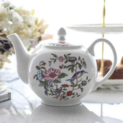 A white ceramic teapot with hand-painted pink, blue, red flowers and bird in an exquisite decorbites tea coffee set
