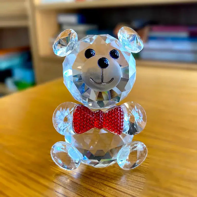 A faceted clear crystal teddy bear figurine with black button eyes and a red jeweled bow tie for bedroom decor