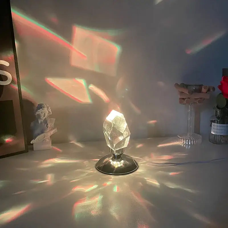 Faceted crystal diamond table lamp with clear prism and metallic base casting colorful rainbow light patterns