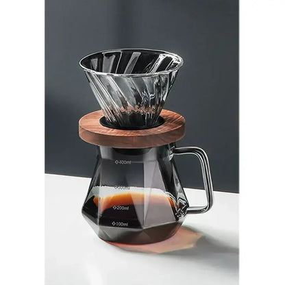 A sleek faceted dark tinted diamond glass coffee carafe with filter cup and wooden base for brewing coffee