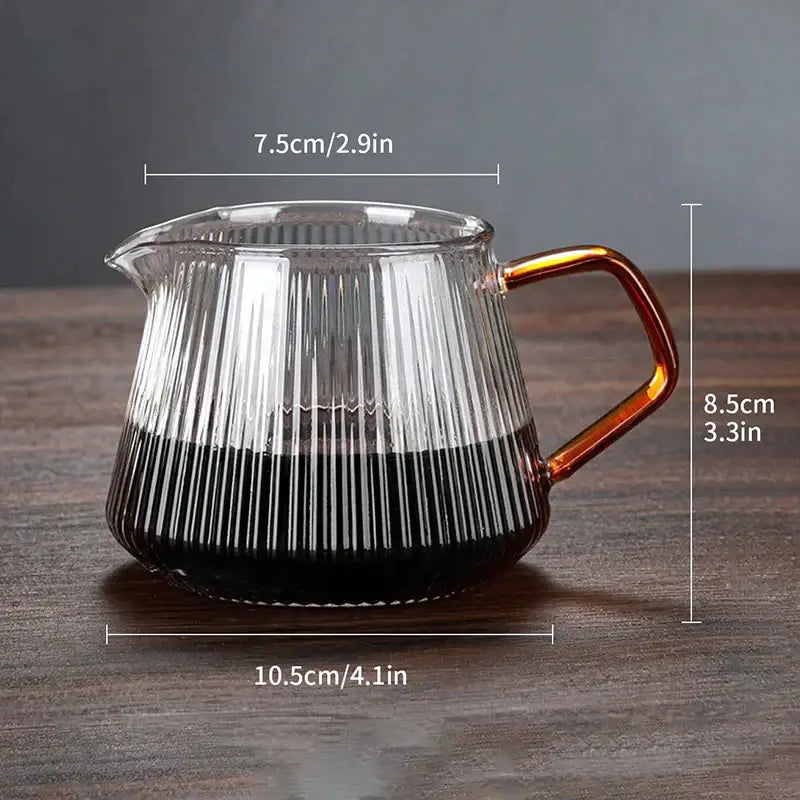 Faceted dark tinted diamond glass coffee carafe with vertical ridges amber handle and filter cup filled with dark liquid