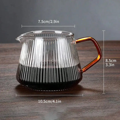 Faceted dark tinted diamond glass coffee carafe with vertical ridges amber handle and filter cup filled with dark liquid