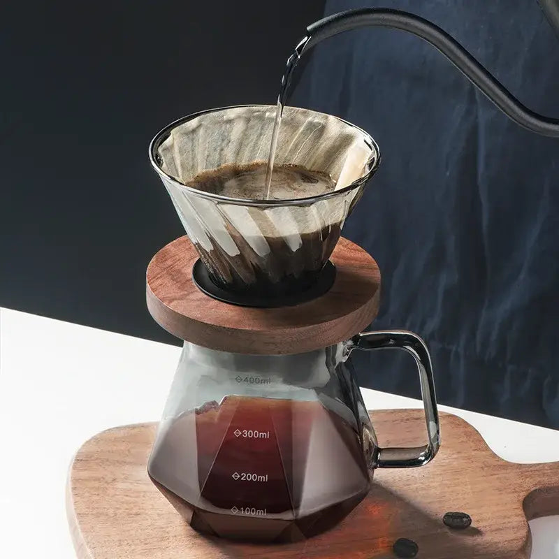 Faceted dark tinted diamond glass coffee carafe with clear glass filter cup and wooden base featuring measurement markings