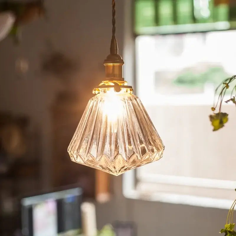 A warm-toned faceted glass pleats led pendant light with brass finish ideal for dining room lighting