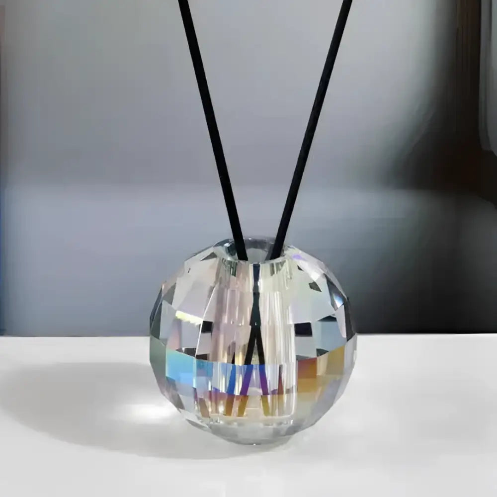 Faceted gold crystal ball aroma diffuser with geometric base and black reed sticks for bedroom decor