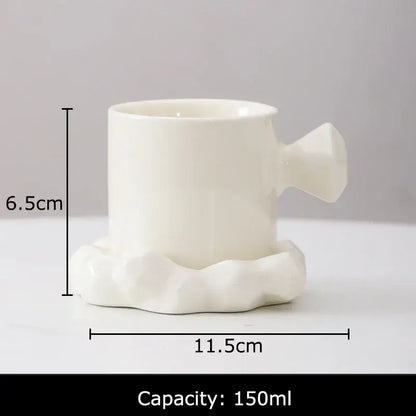 White ceramic coffee mug with sculpted cloud-like base and handle from faceted light blue porcelain mug set