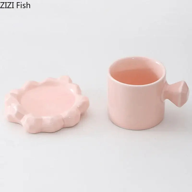Faceted light blue porcelain coffee mug set featuring a pink ceramic coffee mug with matching flower-shaped lid and geometric detailing