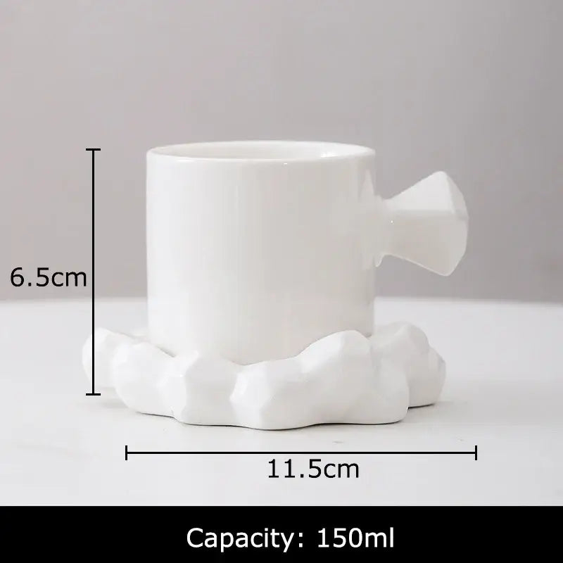 White ceramic coffee mug with geometrically faceted handle and cloud-shaped base in a faceted light blue mug set