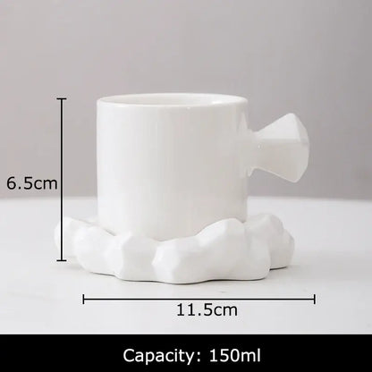 White ceramic coffee mug with geometrically faceted handle and cloud-shaped base in a faceted light blue mug set