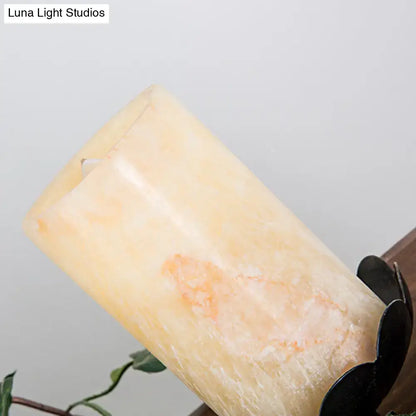 A tall creamy yellow candle with orange veining alongside a farmhouse ivy wooden linear island chandelier