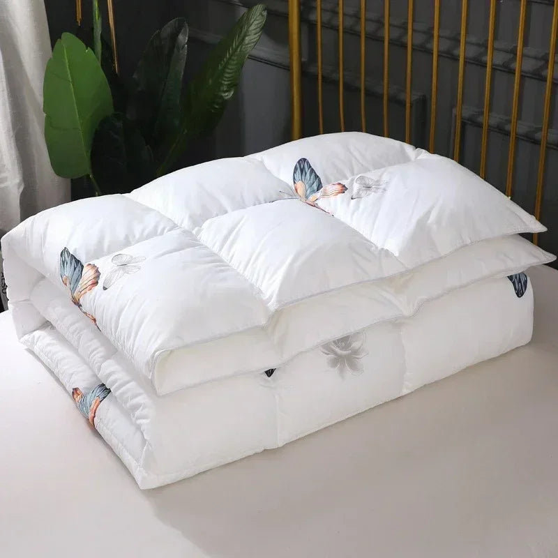 White goose down quilt with white quilted fabric and delicate butterfly embroidery in blue gray and peach tones
