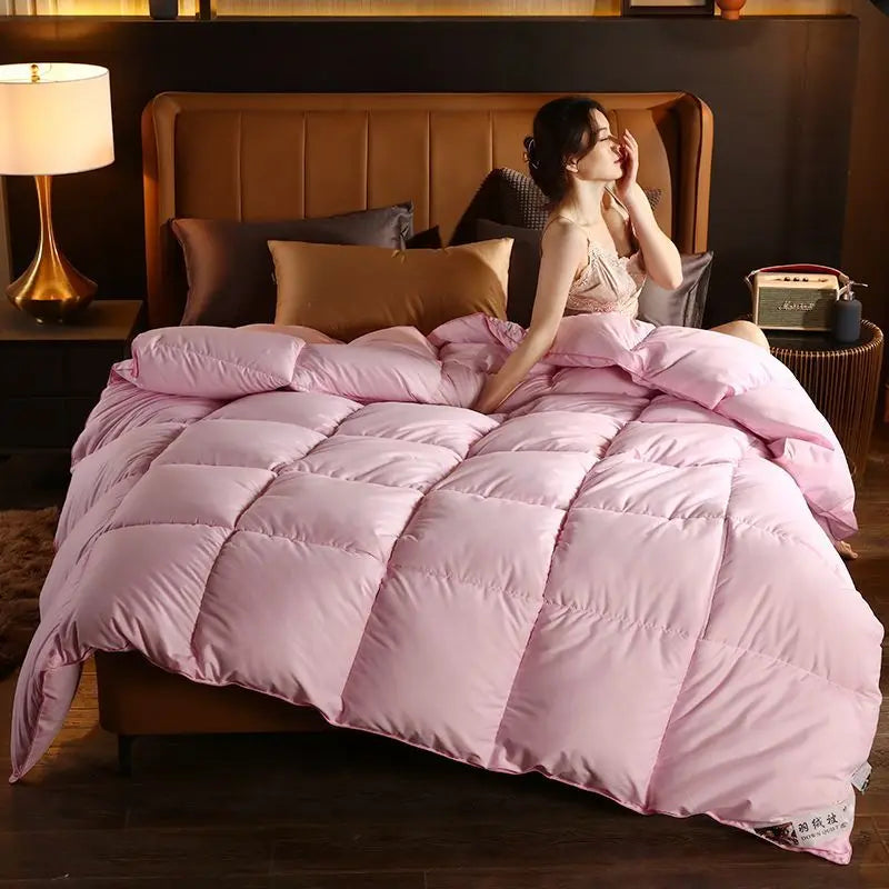 Soft pink quilted comforter with plush texture and subtle stitching made from high-quality white goose down