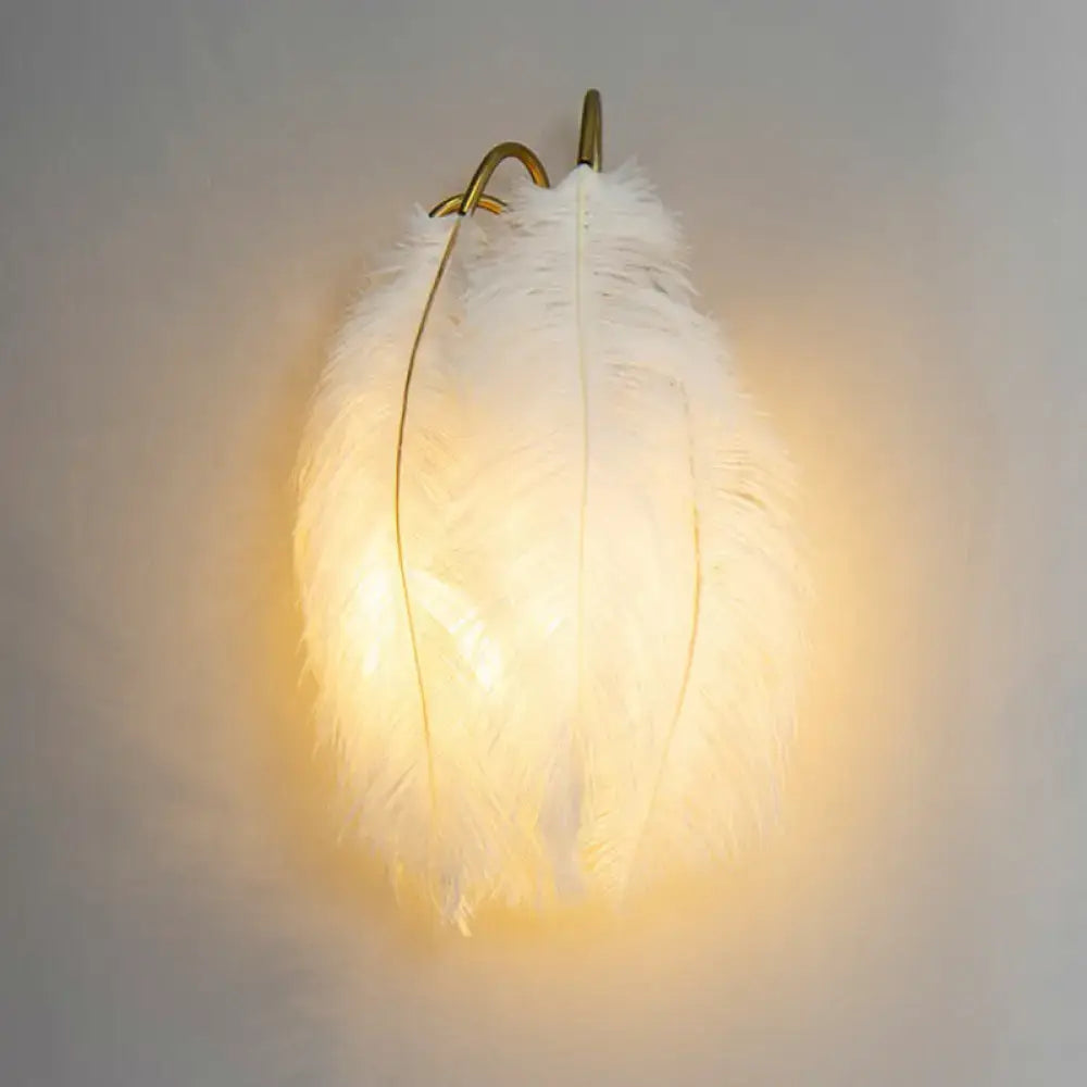 Feather gold wall light fixture with soft glowing white feather shade and gold-toned metal hook for bedroom wall light