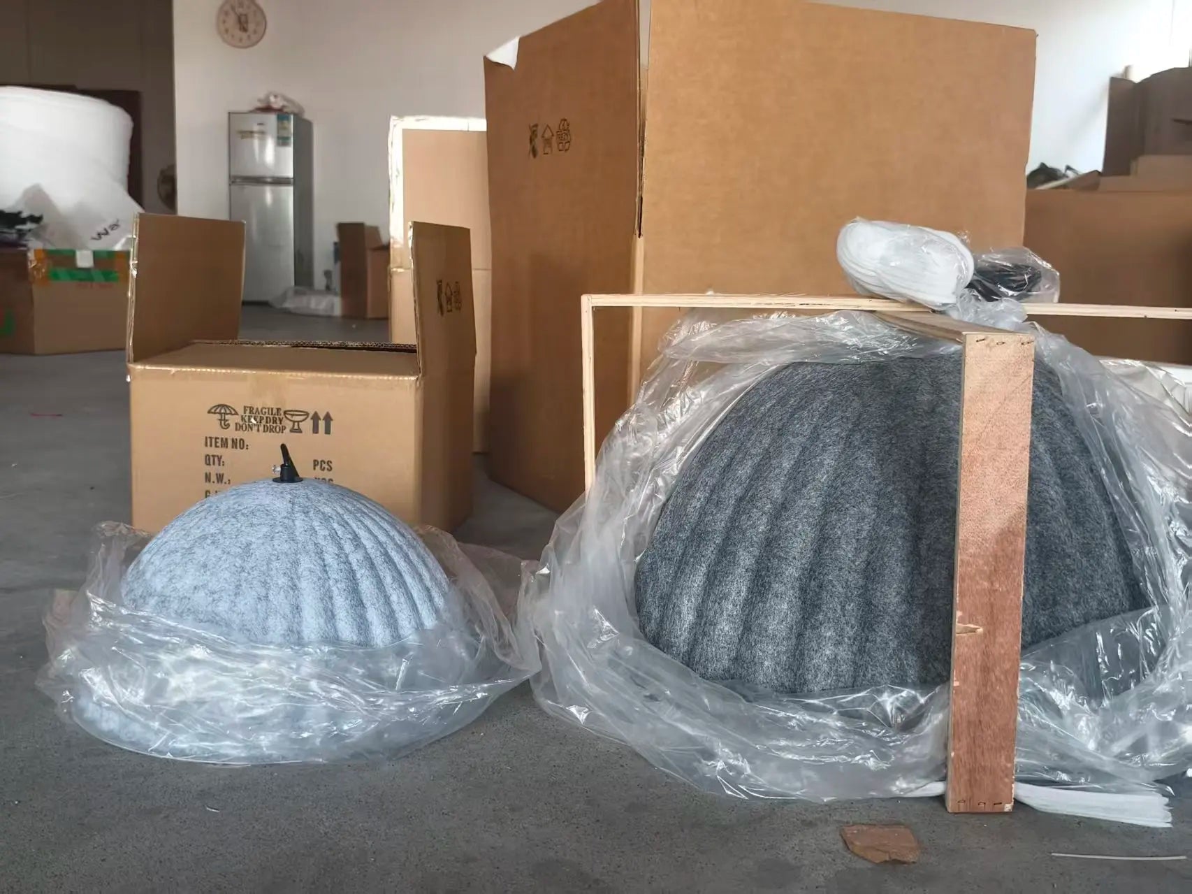 A light blue ribbed felt pendant light acoustic office dome wrapped in clear plastic packaging