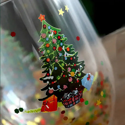 A clear double wall glass mug with a colorful christmas tree sticker and festive confetti for kitchen decor