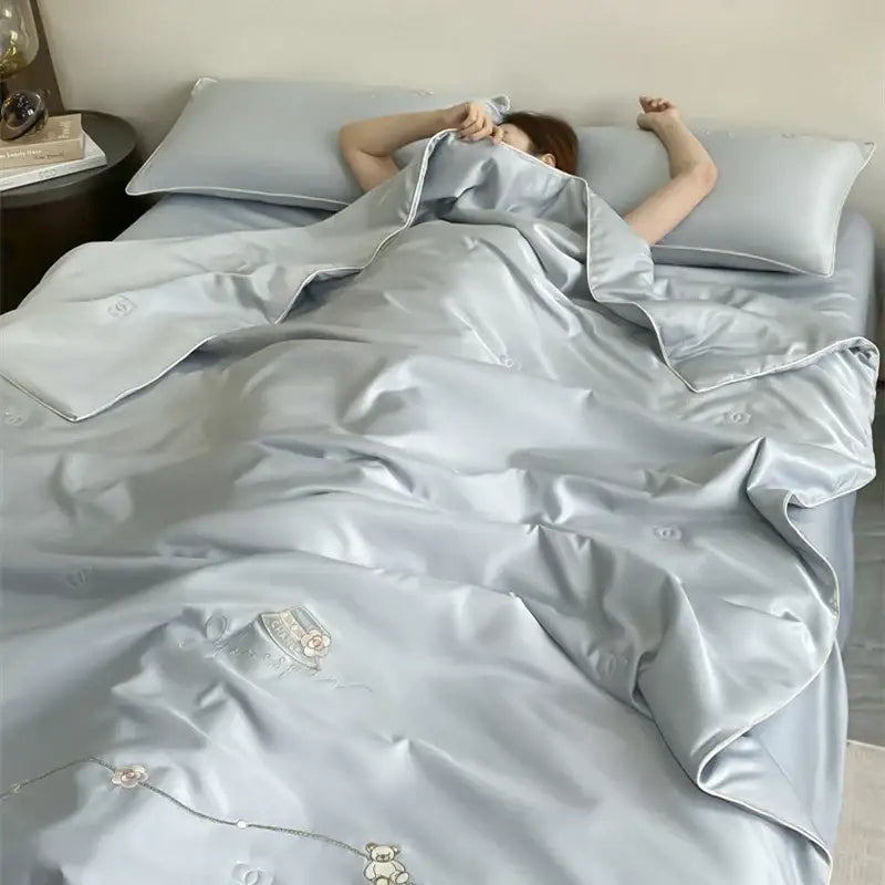 Light blue satin duvet cover with embroidered bear and floral motifs in a floral bear cream and gold summer blanket set