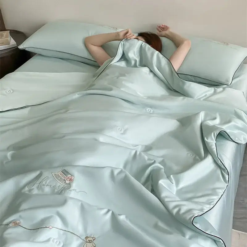 Light blue satin duvet set with subtle embroidery and black piping in a floral bear cream and gold summer blanket set