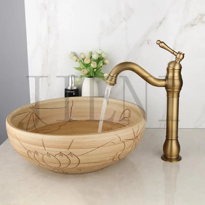 A rustic light-brown wooden vessel sink with lotus engravings and an antique brass faucet for decorbites black ceramics sink set