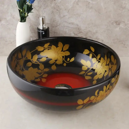 Black ceramic vessel sink with gold floral patterns and red interior paired with swivel brass faucet for bathroom use