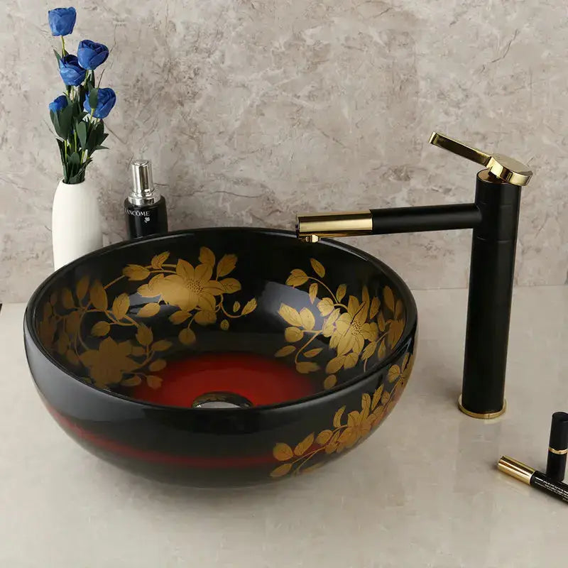 Black ceramic vessel sink with gold floral patterns and red interior paired with a swivel brass faucet