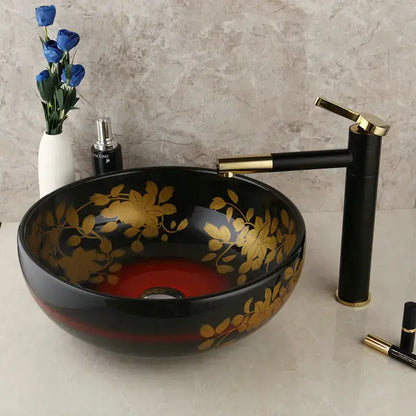Black ceramic vessel sink with gold floral patterns and red interior paired with a swivel brass faucet