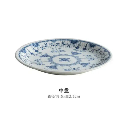 A white ceramic dining plate with delicate blue floral patterns from a floral blue and white ceramic dining set