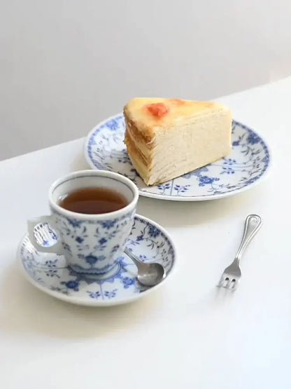 A slice of golden-brown layered cheesecake on a blue and white floral ceramic dining set plate for dining room use