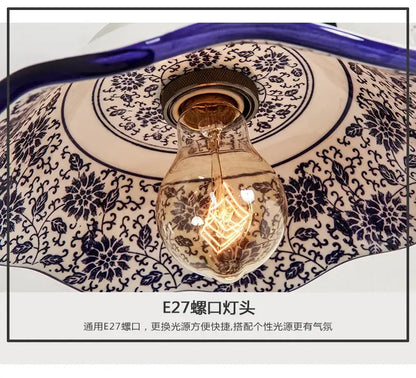 A vintage-style wall lamp with a warm glowing edison bulb housed in a blue white porcelain floral ceramic shade decorbites blue white