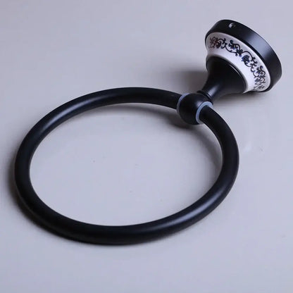 Black stainless steel towel ring with black matte finish and ornate white ceramic base featuring blue floral decorbites design